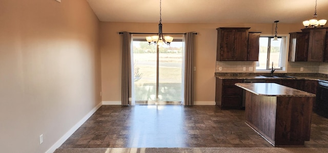 kitchen featuring a wealth of natural light, dark brown cabinetry, decorative backsplash, and hanging light fixtures