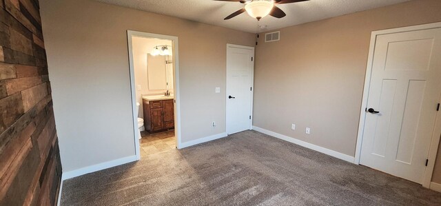 unfurnished bedroom with ensuite bath, sink, carpet flooring, a textured ceiling, and ceiling fan