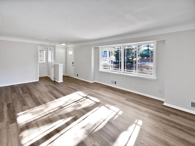 unfurnished living room featuring ornamental molding and hardwood / wood-style flooring