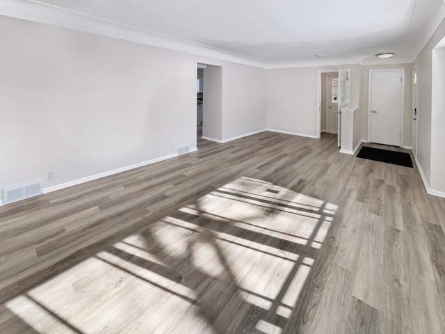 unfurnished living room featuring visible vents, light wood-style flooring, and baseboards