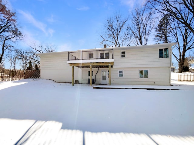 snow covered back of property with a wooden deck