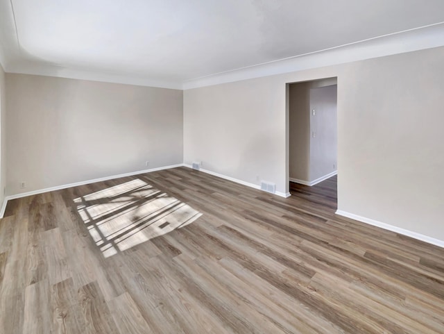 unfurnished room with ornamental molding, visible vents, baseboards, and wood finished floors