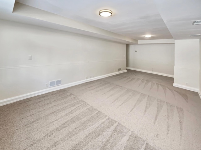 finished below grade area featuring carpet, visible vents, and baseboards