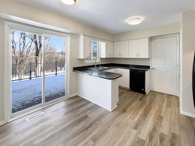 kitchen featuring black dishwasher, visible vents, dark countertops, white cabinetry, and a sink