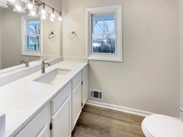 bathroom featuring a healthy amount of sunlight, visible vents, toilet, and vanity