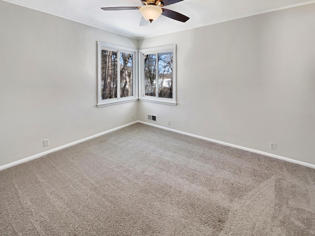 empty room with a ceiling fan, carpet flooring, visible vents, and baseboards