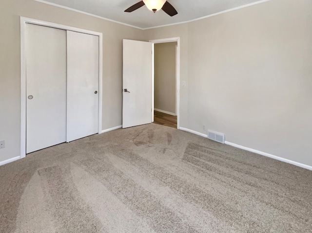 unfurnished bedroom featuring a closet, carpet flooring, visible vents, and crown molding