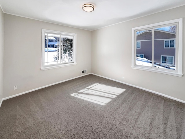 unfurnished room with carpet floors, visible vents, and baseboards