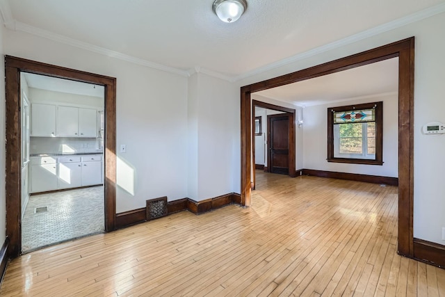 empty room featuring crown molding and light hardwood / wood-style flooring