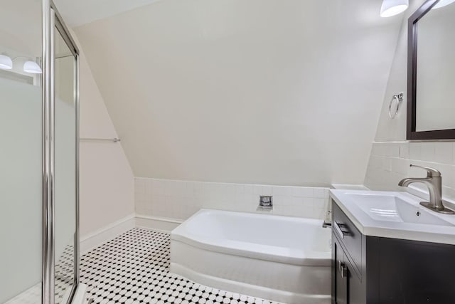 bathroom featuring independent shower and bath, vanity, vaulted ceiling, and decorative backsplash