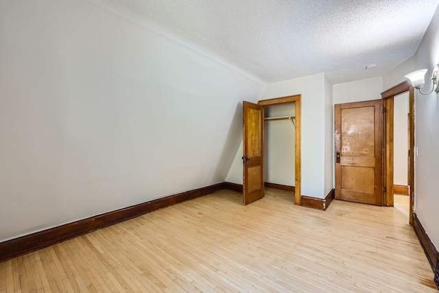 unfurnished bedroom with a textured ceiling, light wood-type flooring, and a closet