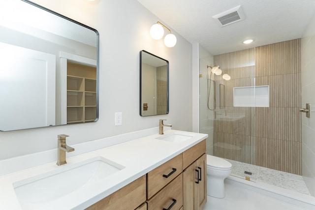 bathroom with tiled shower, vanity, and toilet