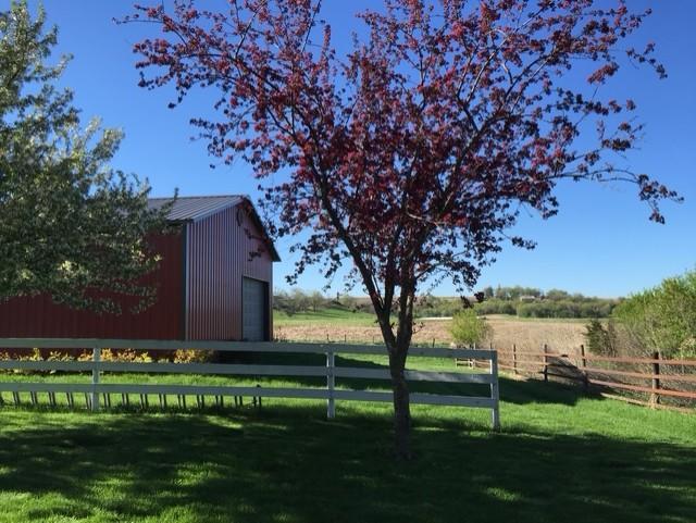 surrounding community with an outdoor structure, a rural view, and a lawn