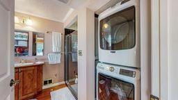 laundry room featuring dark hardwood / wood-style floors, ornamental molding, and stacked washer and clothes dryer