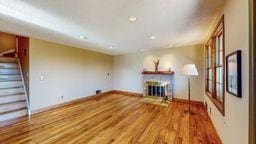 22735 Hickory Rd, Lanesboro, MN 55949 - unfurnished living room with a fireplace, baseboards, wood finished floors, stairs, and recessed lighting