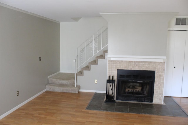 unfurnished living room with ornamental molding, dark wood-type flooring, and a tiled fireplace