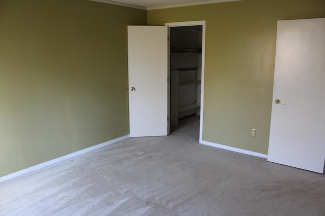 interior space with a closet, crown molding, a spacious closet, and light colored carpet