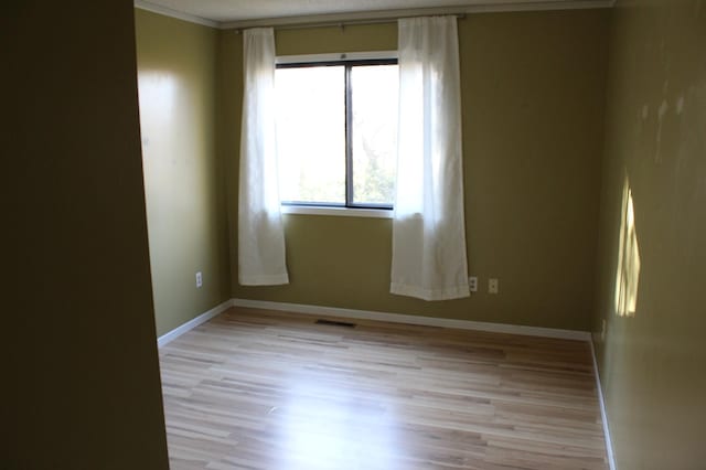 unfurnished room featuring crown molding and light wood-type flooring