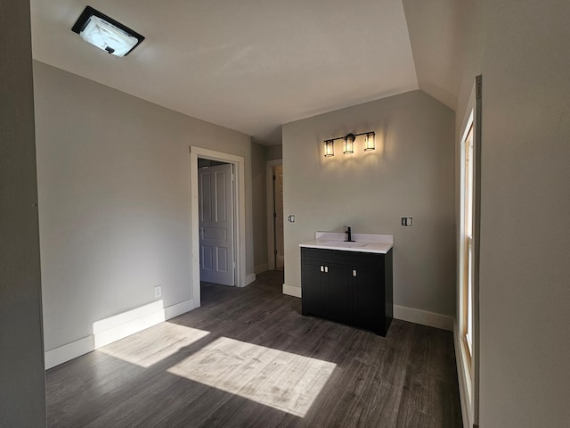 bathroom with a sink, lofted ceiling, baseboards, and wood finished floors