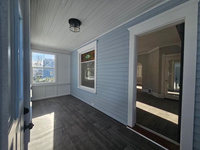 unfurnished sunroom featuring wood ceiling and arched walkways