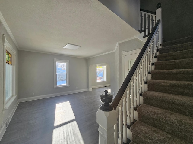 stairway featuring visible vents, a textured ceiling, wood finished floors, crown molding, and baseboards