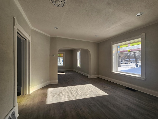 unfurnished room with visible vents, baseboards, ornamental molding, wood finished floors, and arched walkways