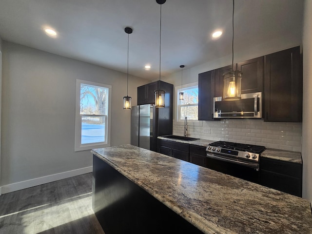 kitchen with tasteful backsplash, baseboards, dark wood finished floors, stainless steel appliances, and a sink