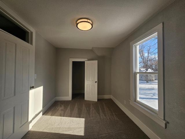 spare room with a wealth of natural light, carpet flooring, a textured ceiling, and baseboards