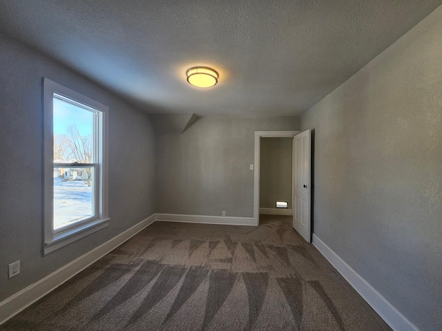 spare room with baseboards, carpet, and a textured ceiling