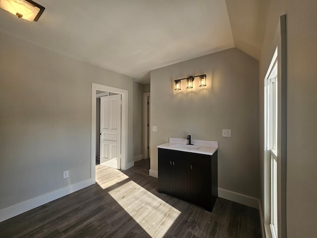 bathroom featuring baseboards, lofted ceiling, and wood finished floors