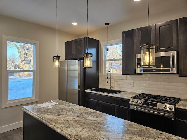 kitchen with baseboards, dark wood-style flooring, a sink, decorative backsplash, and stainless steel appliances