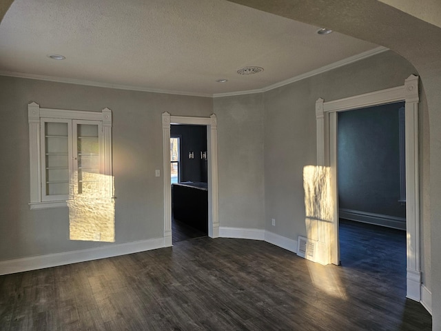 unfurnished room featuring dark wood-type flooring, visible vents, arched walkways, and baseboards