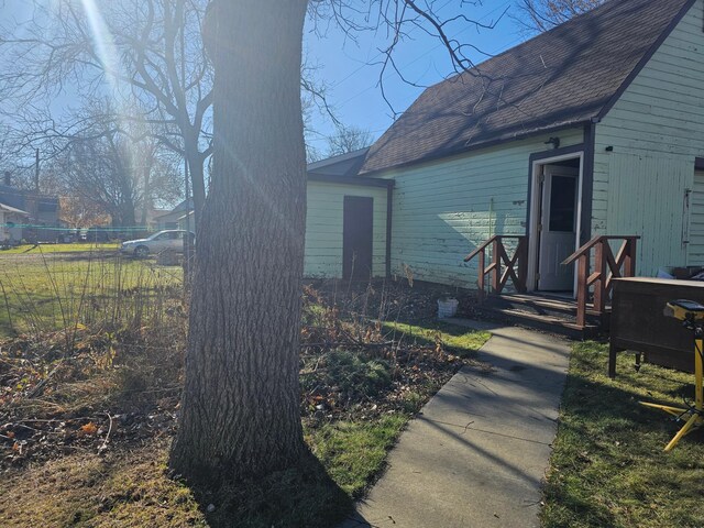 rear view of house featuring roof with shingles and fence