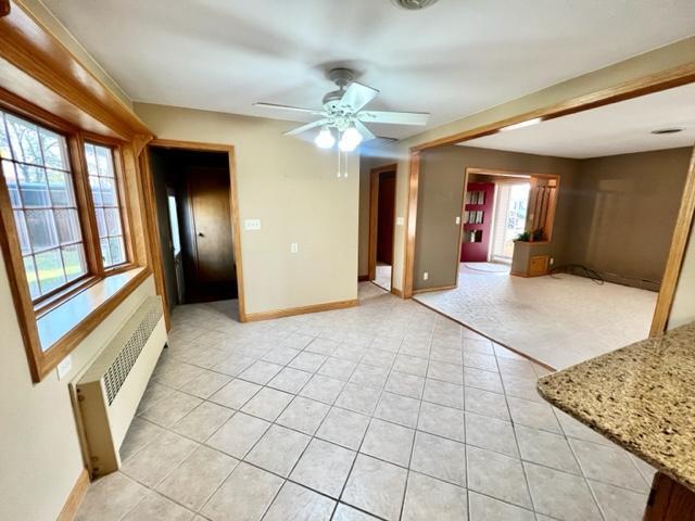 empty room featuring light tile patterned flooring, radiator, and ceiling fan