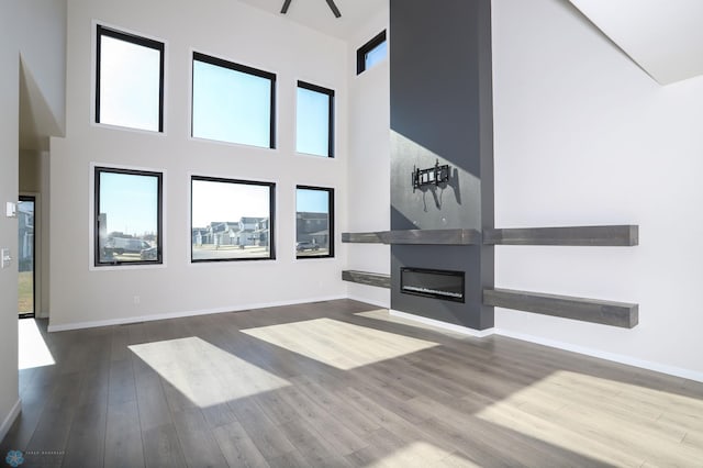 unfurnished living room featuring a towering ceiling, wood-type flooring, and a fireplace