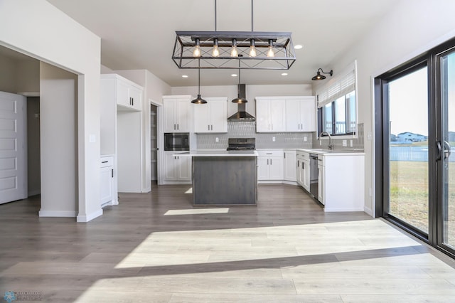 kitchen with wall chimney exhaust hood, plenty of natural light, a kitchen island, and hanging light fixtures