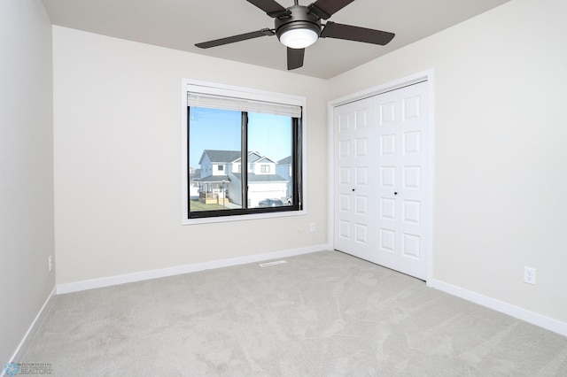 unfurnished bedroom with light colored carpet, a closet, and ceiling fan