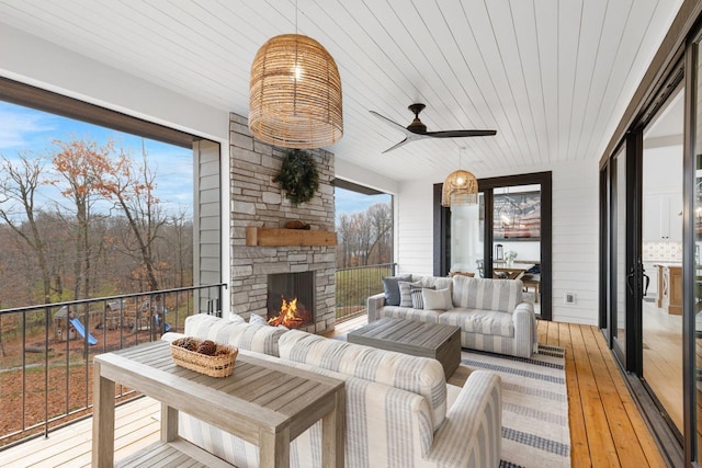 sunroom featuring ceiling fan, wooden ceiling, and a fireplace