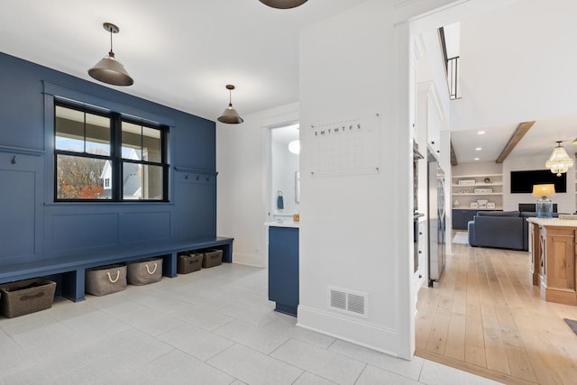 mudroom featuring built in shelves and beam ceiling