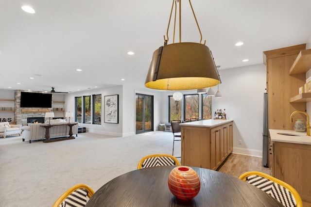 carpeted dining space with a fireplace, ceiling fan, and sink