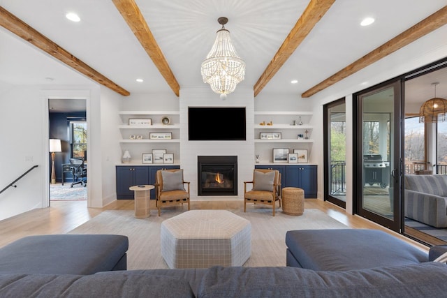 living room featuring a large fireplace, a healthy amount of sunlight, beamed ceiling, and light wood-style flooring