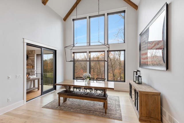 dining area with visible vents, baseboards, light wood-style flooring, high vaulted ceiling, and beam ceiling