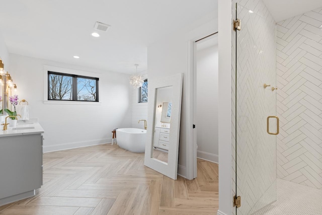 bathroom with recessed lighting, a stall shower, vanity, a freestanding tub, and baseboards