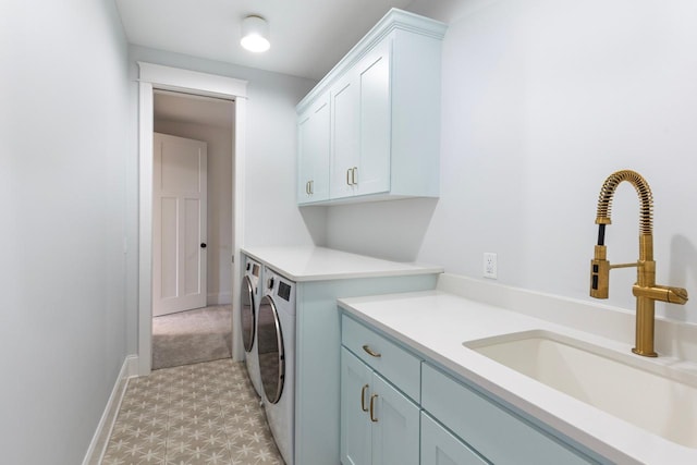 laundry room featuring cabinet space, baseboards, independent washer and dryer, light floors, and a sink