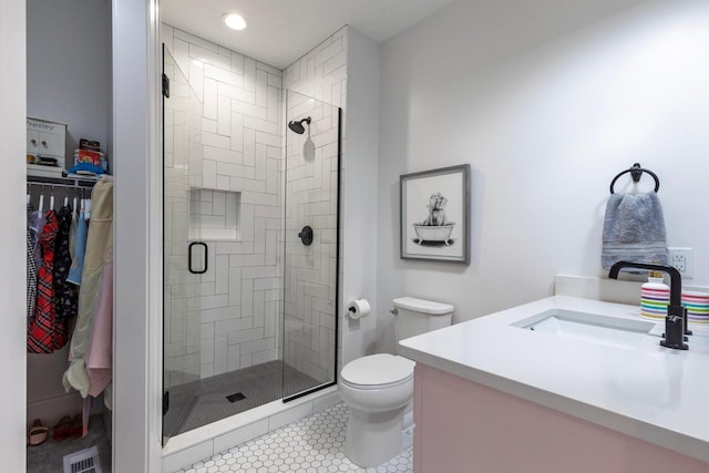 bathroom featuring a walk in closet, visible vents, toilet, a shower stall, and vanity