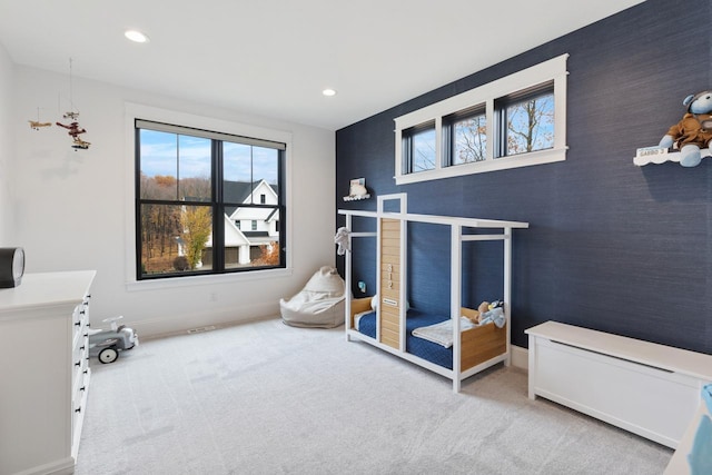 bedroom featuring baseboards, an accent wall, multiple windows, and light colored carpet