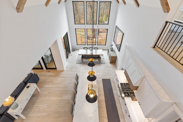 living area with a towering ceiling, light wood-type flooring, stairway, and beamed ceiling