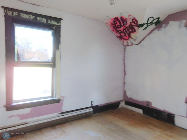 spare room featuring baseboard heating, vaulted ceiling, and plenty of natural light