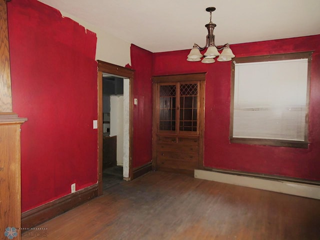 unfurnished dining area with a baseboard radiator, dark wood-type flooring, and an inviting chandelier