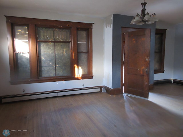 empty room featuring a notable chandelier, hardwood / wood-style flooring, and a baseboard radiator